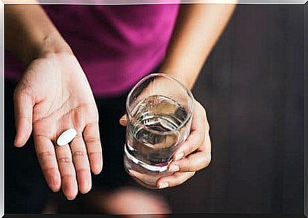 Person with paracetamol and a glass of water in hand