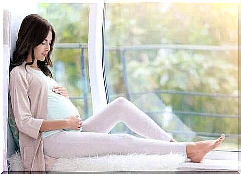 A pregnant woman is sitting on a windowsill and needs the support of the family during pregnancy.