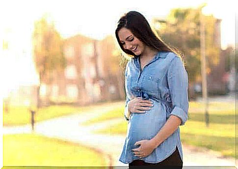 A pregnant woman is walking outside.